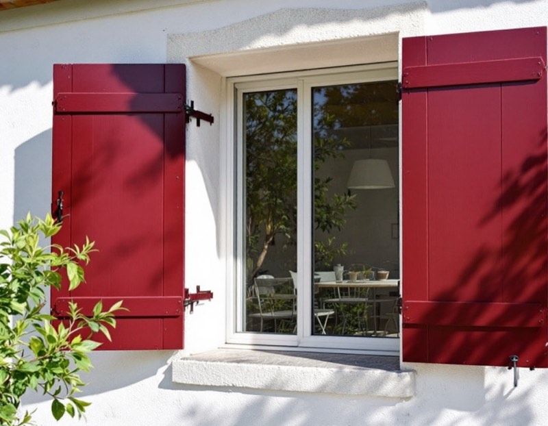 Volets battants aluminium rouge sur une façade blanche